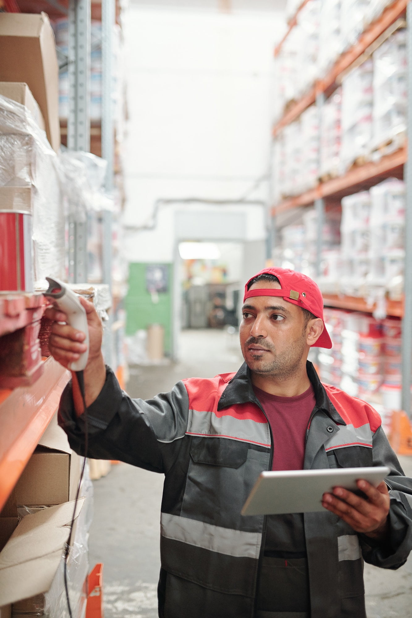 Mixed-race male worker of warehouse in uniform scanning qr codes on boxes